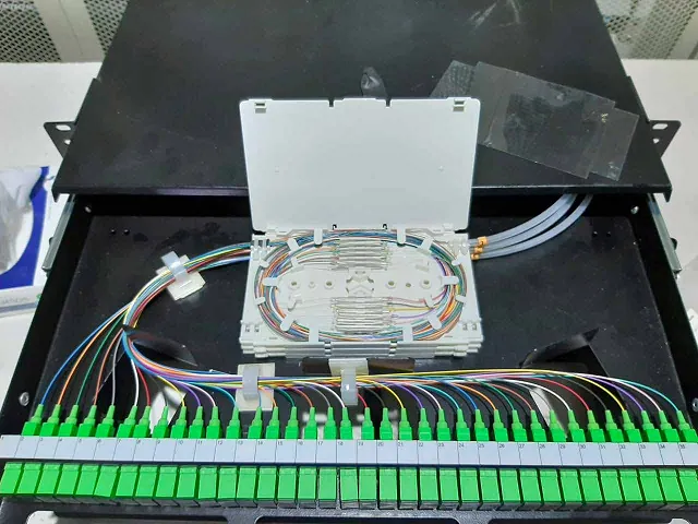 Bandeja de empalme de un distribuidor óptico con pigtails de colores y regleta de conectores SC/APC