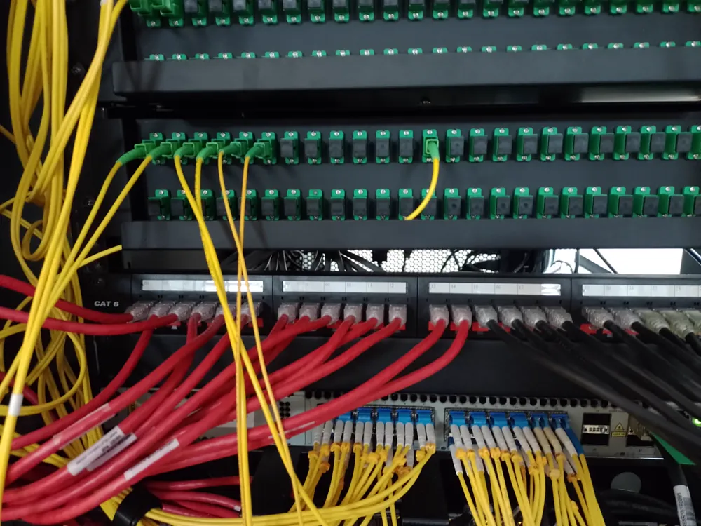 Rack de distribución óptica con patcheras SC/APC, patchcords amarillos y patchera Cat 6